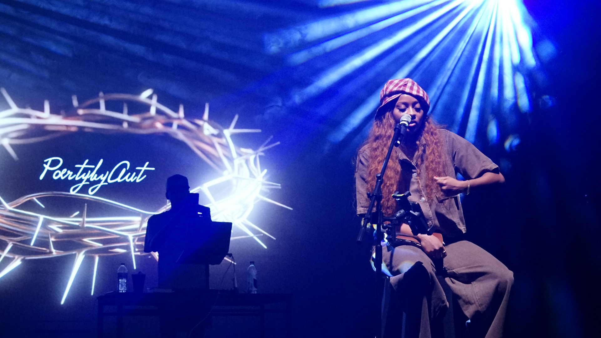 Aut performing live with the PoetrybyAut crown of thorns projection